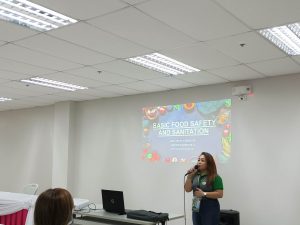 in photo: Ms. April Wendy S. Ponce, Sanitation Inspector III from the City Health Office, leading the discussion on various food safety topics.