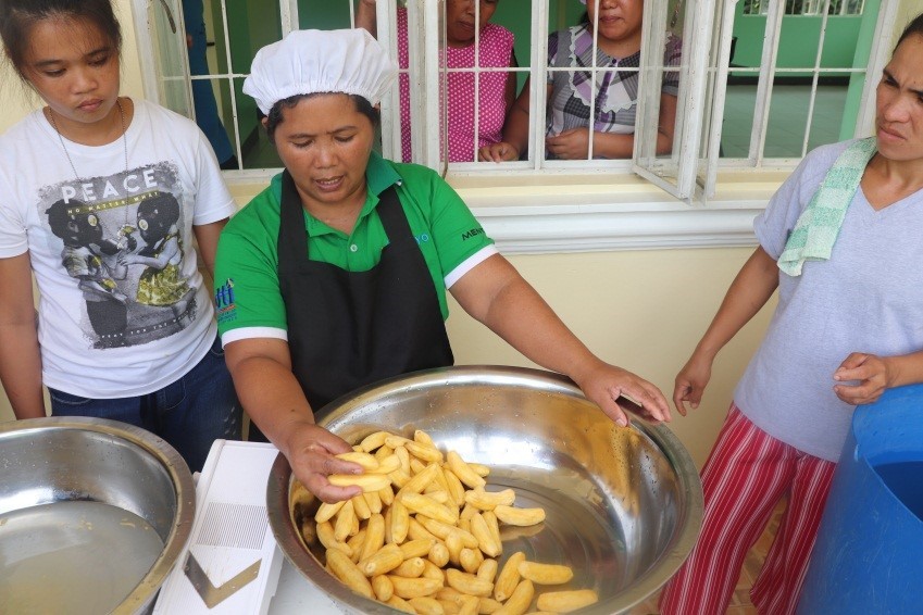 An assisted banana-chips producer demonstrates how to properly wash and select the best bananas for the chips