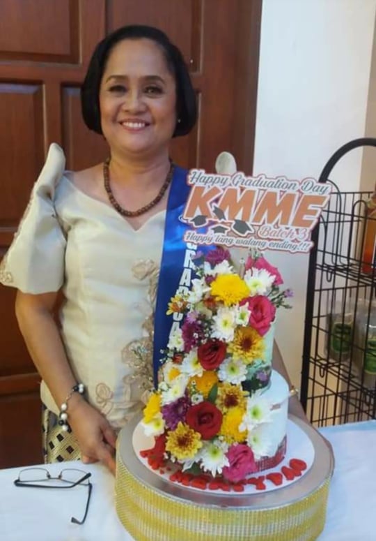 Cynthia Orozco Acevedo standing before a cake for her KMME Graduation Day.