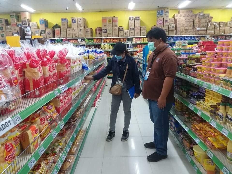 Photo of DTI-Region 1 employee inspecting the price of canned goods at a grocery store as part of the Department's price monitoring of Basic Necessities and Prime Commodities (BNPCs)