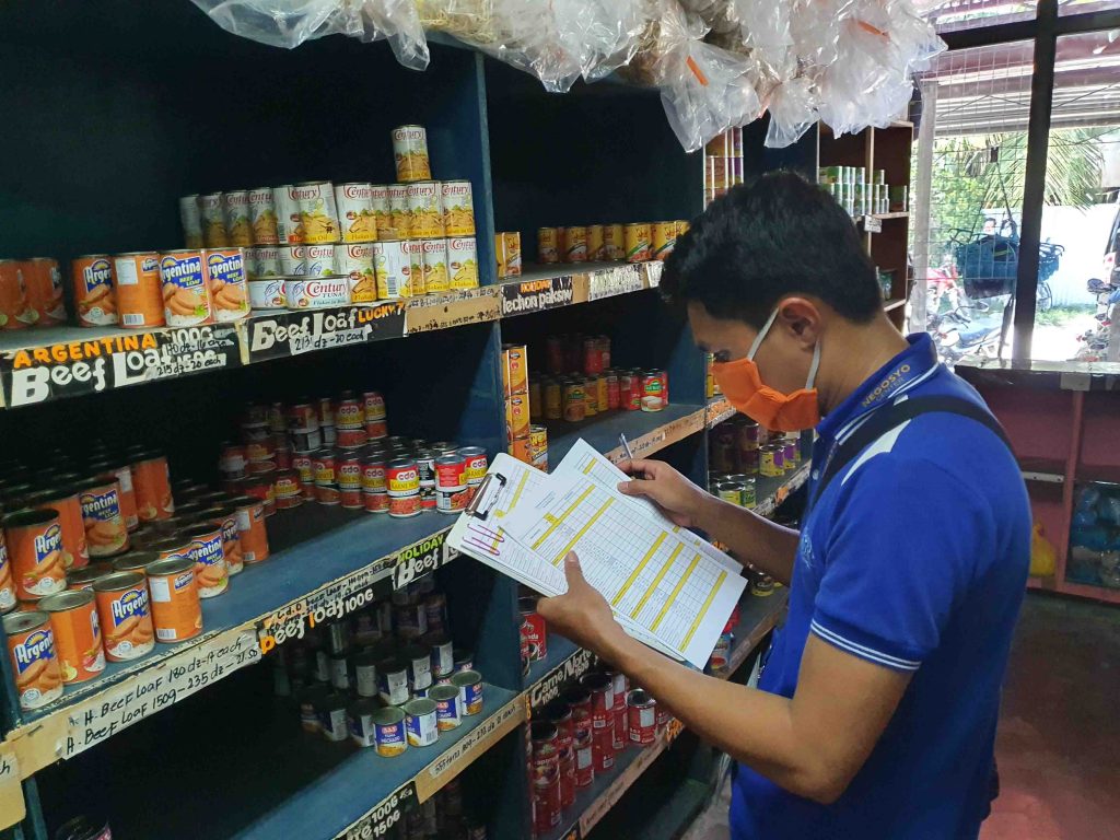 A staff monitoring variety of canned goods in a grocery store in Davao Occidental