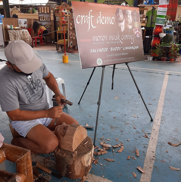 Local Mogpog artisan Salvador "Buddy" Liwanagan bends over carving a Morion mask