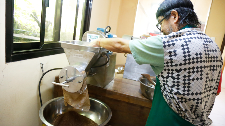 One of the farms' employees grinding the coffee beans