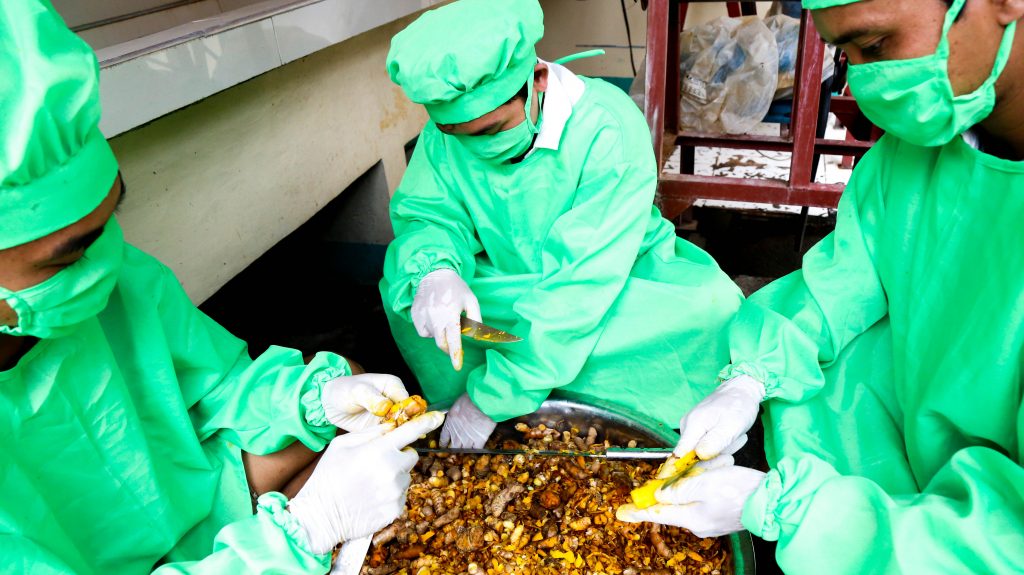 Manna’s Alternative Herbal Products’ Staff peeling turmeric ginger