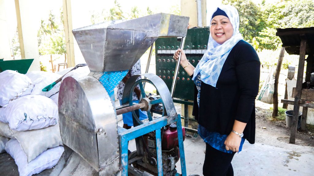 MMPC Chairperson Maria Nisa Suib cheerfully poses beside their manufacturing equipment