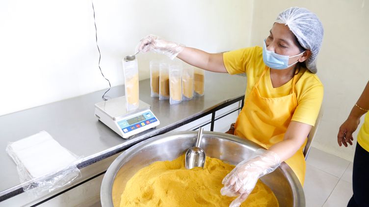 An employee of Mira’s Turmeric Products scooping turmeric powder to be weighed before being packed