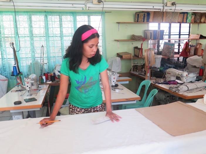 A Kilusang Kabalikat ng mga may Kapansanan para sa Kinabukasan member working on a pattern or padron for a bag