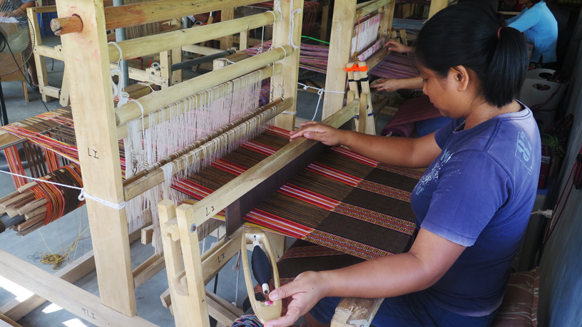 An employee weaving enabel on a loom