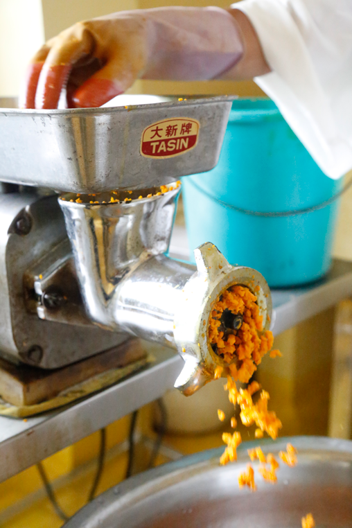 A member of MIWA putting turmeric roots through a pulverizer machine